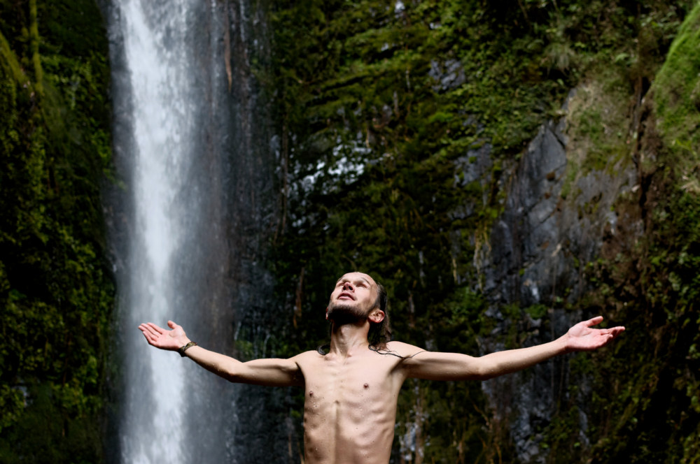 Friend Mateusz spreads his hands in delight on a mescaline trip over a waterfall